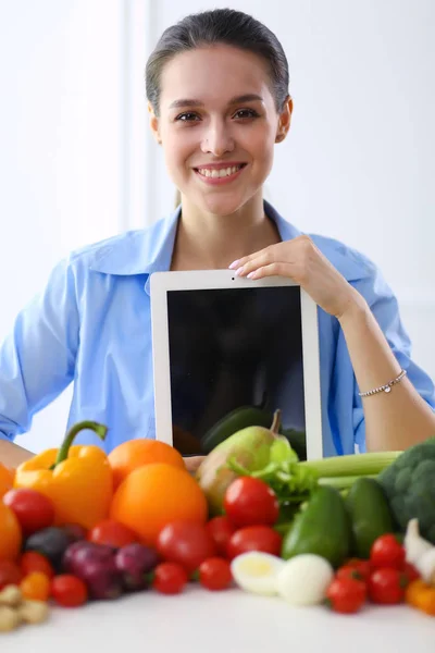 Mulher jovem e bonito sentado à mesa cheia de frutas e legumes no interior de madeira — Fotografia de Stock