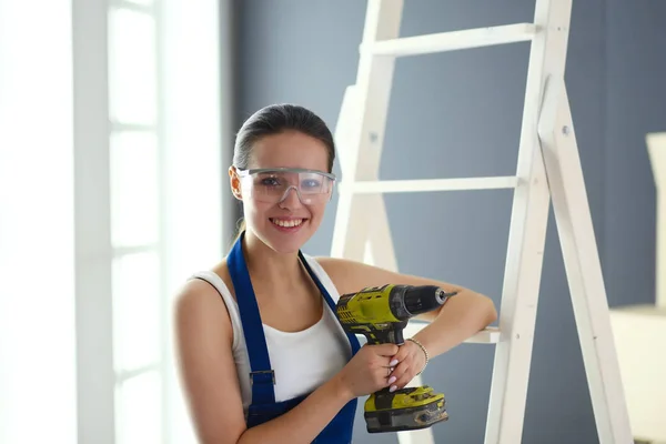 Travailleur femme avec perceuse debout dans une nouvelle maison — Photo