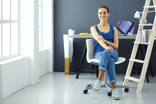 Mujer joven sentada en el escritorio con instrumentos, plano y portátil — Foto de Stock