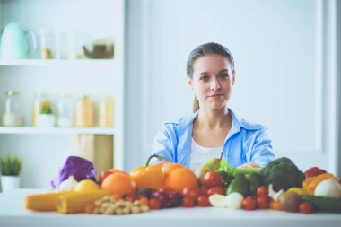 Ahşap iç kısımda meyve ve sebze dolu masada oturan genç ve tatlı bir kadın.