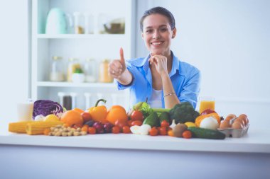 Ahşap iç kısımda meyve ve sebze dolu masada oturan genç ve tatlı bir kadın.