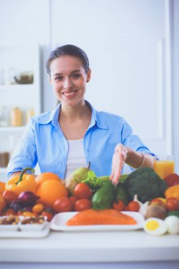 Ahşap iç kısımda meyve ve sebze dolu masada oturan genç ve tatlı bir kadın.