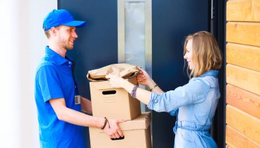 Mavi üniformalı gülümseyen kurye servis konseptine paket kutusu teslim eden teslimatçı. Mavi üniformalı gülümseyen teslimatçı.