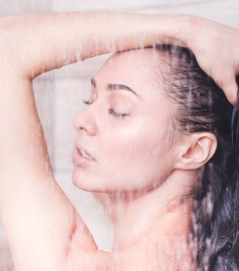 Genç beautyful kadın banyoda duş altında.