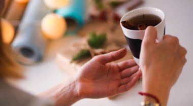 Noel hediye kutusu ile masaya oturan kadın. Kadının elleri