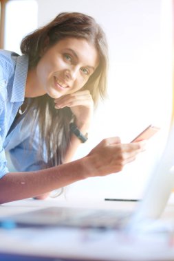 Ofis masasında oturan ve cep telefonuyla konuşan genç ve güzel bir iş kadını. İş kadını
