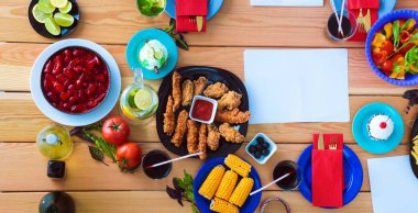 Ahşap masada otururken birlikte yemek yiyen bir grup insanın üst düzey görüntüsü. Masada yemek var. İnsanlar fast food yiyor..