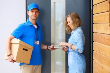 Mavi üniformalı gülümseyen kurye servis konseptine paket kutusu teslim eden teslimatçı. Mavi üniformalı gülümseyen teslimatçı.