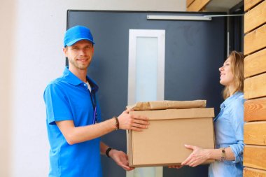 Mavi üniformalı gülümseyen kurye servis konseptine paket kutusu teslim eden teslimatçı. Mavi üniformalı gülümseyen teslimatçı.