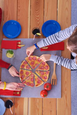 Ahşap masada otururken birlikte yemek yiyen bir grup insanın üst düzey görüntüsü. Masada yemek var. İnsanlar fast food yiyor..