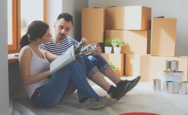 Yeni evin içini boyayan mutlu, gülümseyen genç bir çift portresi. Genç çift