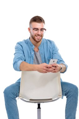 Sandalyede oturan ve cep telefonuyla genç adam. Startupper. Genç girişimci.