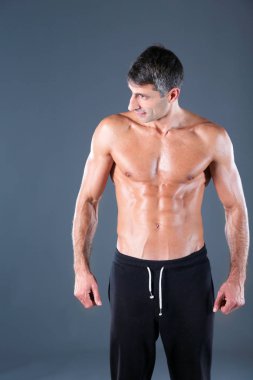 kaslı adam. Kaslı adam kas gösterilen gri arka plan üzerinde. Fitness Eğitmeni. Fitness profesyonel. Egzersiz. Mens fitness.