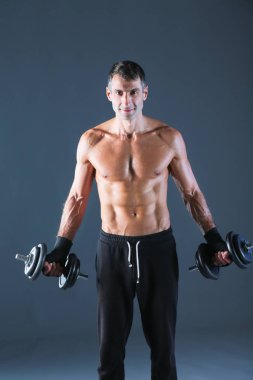 Yakışıklı kaslı adam dumbell ile çalışma dışarı. Kişisel fitness eğitmeni. Kişisel eğitim.