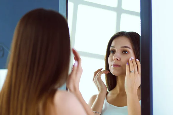 Mujer joven mirándose a sí misma reflejo en el espejo en casa —  Fotos de Stock