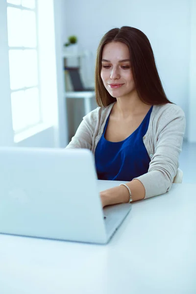 Hermosa mujer joven utilizando el ordenador portátil en el escritorio —  Fotos de Stock