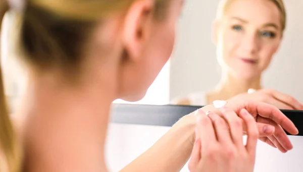 Woman caring of her beautiful skin on the face standing near mirror — Stock Photo, Image