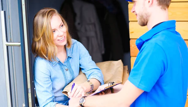 Repartidor sonriente con uniforme azul que entrega la caja de paquetes al destinatario: concepto de servicio de mensajería. Repartidor sonriente en uniforme azul — Foto de Stock