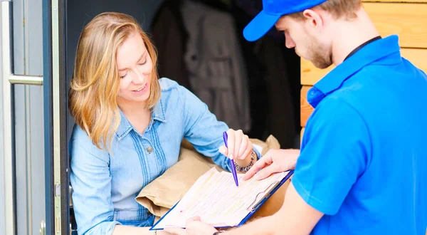 Mavi üniformalı gülümseyen kurye servis konseptine paket kutusu teslim eden teslimatçı. Mavi üniformalı gülümseyen teslimatçı.
