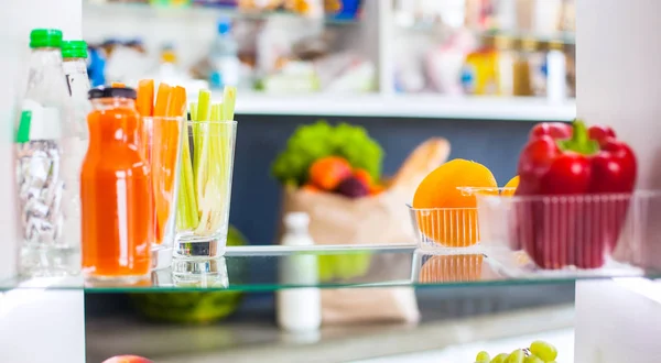 Portrait of female standing near open fridge full of healthy food, vegetables and fruits. Portrait of female — Stock Photo, Image