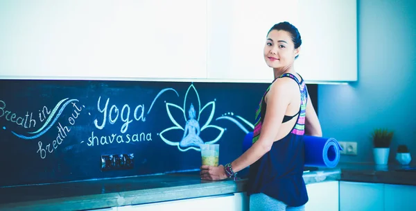 Retrato de una mujer sonriente sosteniendo en su mano una esterilla de yoga mientras estaba de pie en el estudio. Yoga. Una mujer. Bienestar — Foto de Stock