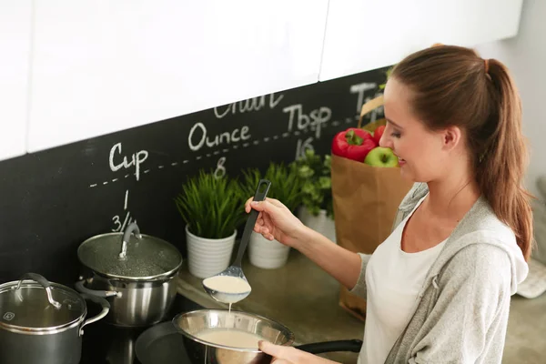 Genç bayan masanın yanında dururken mutfakta krep hazırlıyor. Mutfaktaki kadın. Mutfakta yemek yapmak..