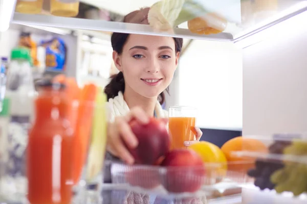 Portrait of female standing near open fridge full of healthy food, vegetables and fruits. Portrait of female — Stock Photo, Image