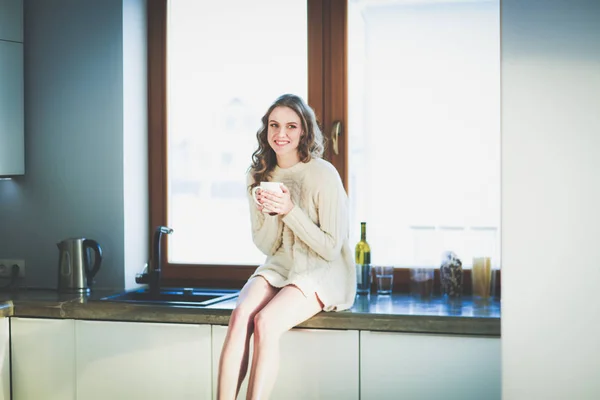 Retrato de uma mulher segurando uma xícara de chá em sua cozinha . — Fotografia de Stock