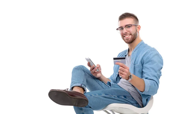 年轻男子坐在椅子上，拿着信用卡。Startupper。年轻的企业家. — 图库照片