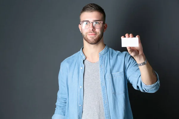 Junger Mann mit einer Kreditkarte auf grauem Hintergrund. Jungunternehmer. — Stockfoto