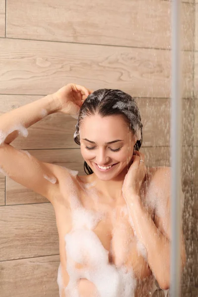 Junge schöne Frau unter der Dusche im Badezimmer. — Stockfoto