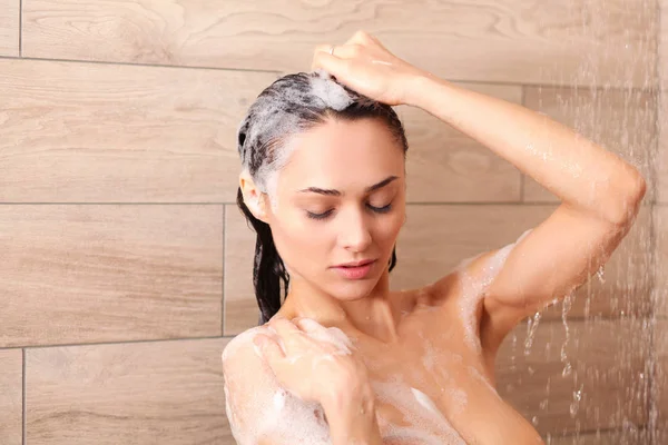 Joven mujer hermosa bajo la ducha en el baño . — Foto de Stock