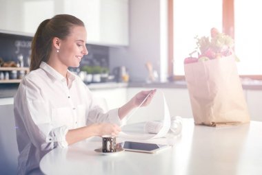 Giderleri planlama ve mutfağını faturalarında ödeme genç kadın.
