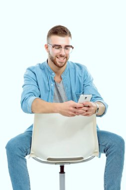Sandalyede oturan ve cep telefonuyla genç adam. Startupper. Genç girişimci.