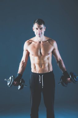 Yakışıklı kaslı adam dumbell ile çalışma dışarı. Kişisel fitness eğitmeni. Kişisel eğitim.