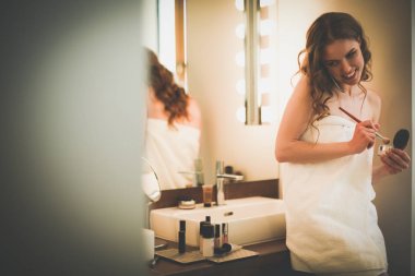 Telefon ile banyo üzerinde duran genç kadın.