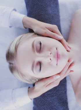 Masaj masasında uzanmış gözleri kapalı rahatlayan genç bir kadın. - Kadın. Spa salonu