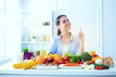 Ahşap iç kısımda meyve ve sebze dolu masada oturan genç ve tatlı bir kadın.
