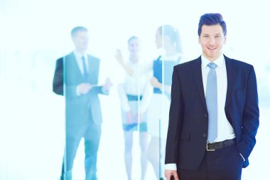 Arka planda meslektaşları olan genç iş adamının portresi. Genç iş adamının portresi.