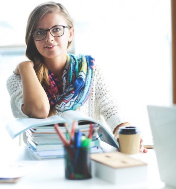 Kitapların arasında masa başında oturan genç bir kadın.