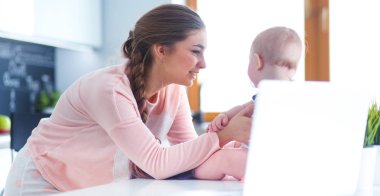 Annesi bebeğini evde parlak mutfakta ile.