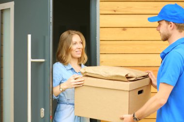 Mavi üniformalı gülümseyen kurye servis konseptine paket kutusu teslim eden teslimatçı. Mavi üniformalı gülümseyen teslimatçı.