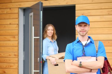 Mavi üniformalı gülümseyen kurye servis konseptine paket kutusu teslim eden teslimatçı. Mavi üniformalı gülümseyen teslimatçı.