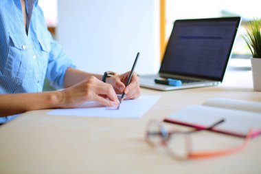 Ofis masasında dizüstü bilgisayarla oturan genç bir kadın. Genç bir kadın. Dizüstü bilgisayar