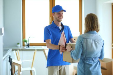 Mavi üniformalı gülümseyen kurye servis konseptine paket kutusu teslim eden teslimatçı. Mavi üniformalı gülümseyen teslimatçı.
