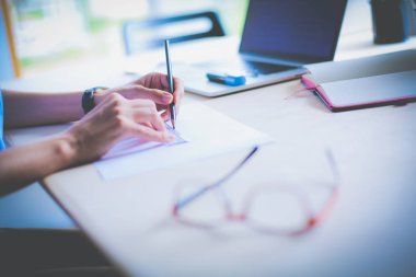 Ofis masasında dizüstü bilgisayarla oturan genç bir kadın. Genç bir kadın. Dizüstü bilgisayar
