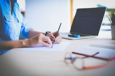 Ofis masasında dizüstü bilgisayarla oturan genç bir kadın. Genç bir kadın. Dizüstü bilgisayar