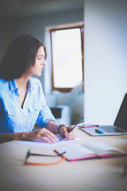 Ofis masasında dizüstü bilgisayarla oturan genç bir kadın. Genç bir kadın. Dizüstü bilgisayar