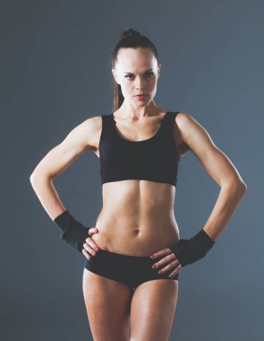 Gri arka plan üzerinde duran kas genç kadın. Kas genç kadın