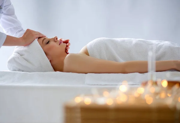 Mujer joven acostada en una mesa de masaje, relajándose con los ojos cerrados. Una mujer. Salón de spa — Foto de Stock